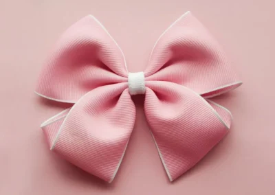 Pink polka dot hair bow with white edges and a large, neatly tied ribbon featuring white spots on a light pink background.